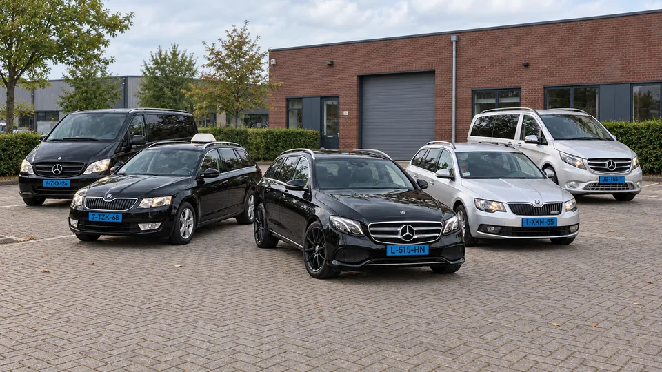 De twee Mercedes-taxibussen, twee Škoda stationwagens en zwarte Mercedes E220 van City Taxi samen op een verzorgd voorplein.