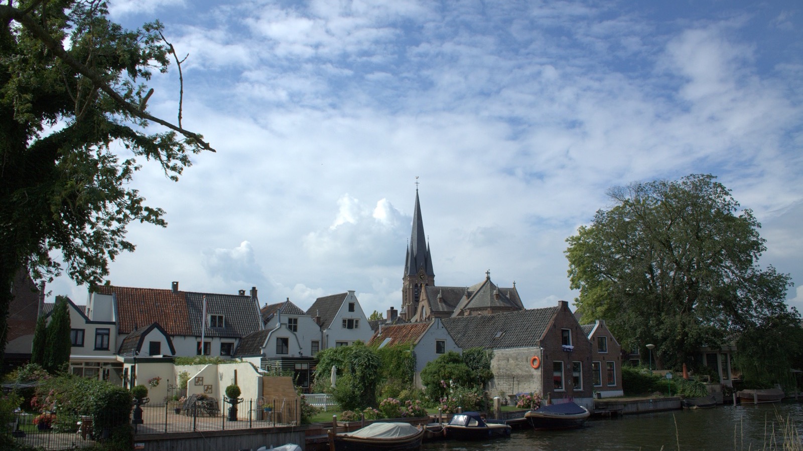 Breukelen aan de Vecht met huizen aan het water en de kerktoren op de achtergrond.