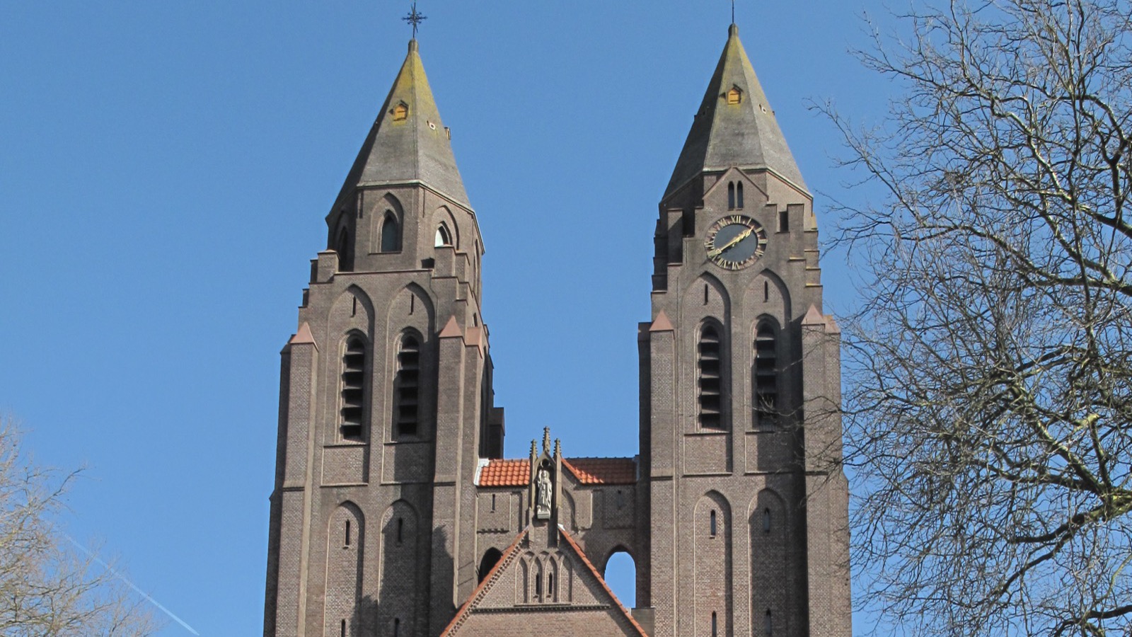De Sint-Jansbasiliek in Laren met haar twee torens onder een blauwe lucht.